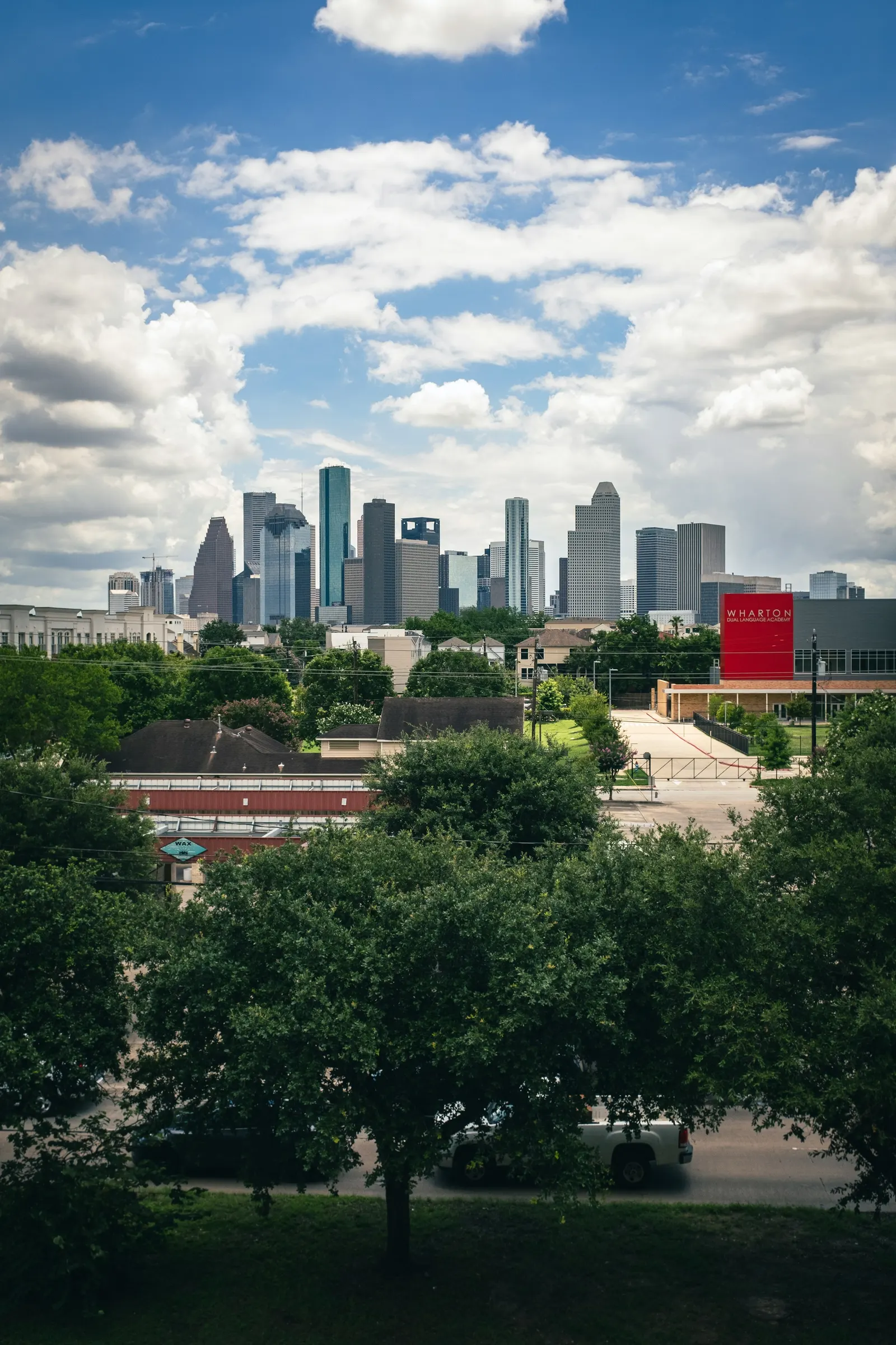 Houston downtown skyline visible behind a tree-lined neighborhood